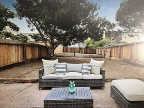 A backyard with a wicker sofa, a small table, and a tree providing shade. - San Francisco Retreat Near Ocean Beach (San Francisco)