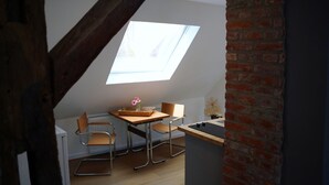 A loft bedroom with a skylight, a wooden desk, two chairs, a radiator, and a brick wall. - Old Town Apartment Hameln App 1 (Hameln)