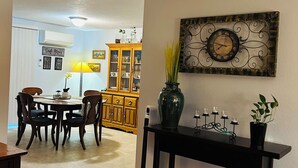Ein Essbereich mit Holztisch und Stühlen, einer Vitrine und einer Wanduhr.