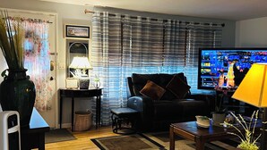 Ein Wohnzimmer mit einer Couch, einem Couchtisch, einem Fernseher und einer Lampe.