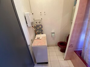 A compact bathroom with a white toilet, a shower area, and a small sink with a floral-patterned shower curtain. - Apartment in a residential complex with a spectacular view and parking space (Font-Romeu-Odeillo-Via)