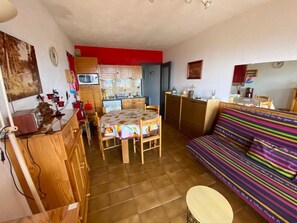 A compact living space with a dining area, kitchenette, and a colorful sofa. - Apartment in a residential complex with a spectacular view and parking space (Font-Romeu-Odeillo-Via)