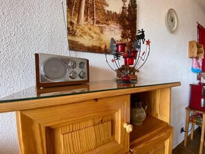 A wooden cabinet with a radio on top and a decorative metal piece below.