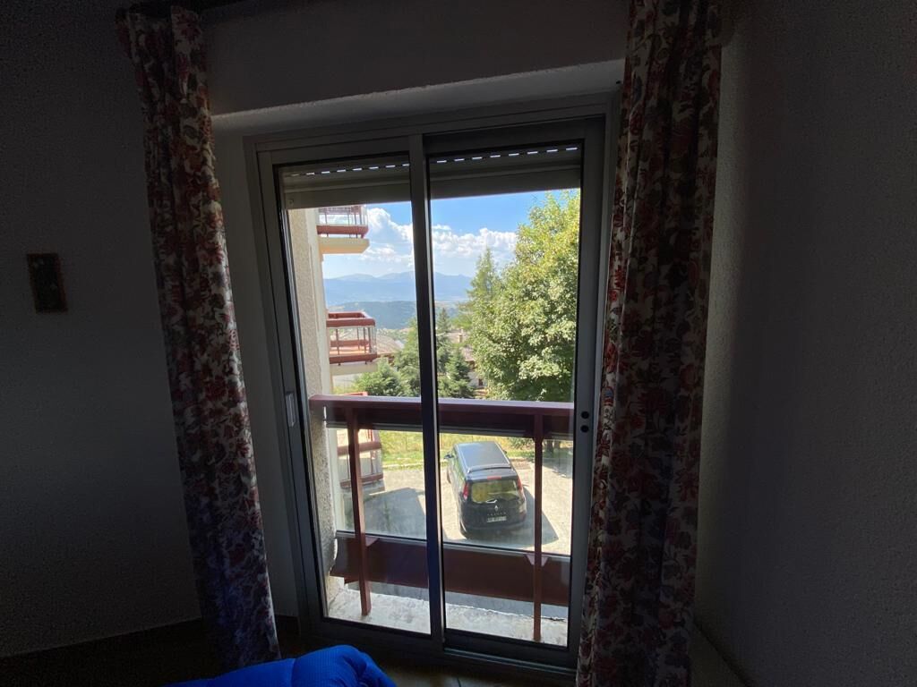 A room with a large sliding glass door leading to an outdoor area with a wooden deck and a car parked outside.