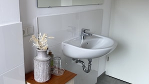 Une salle de bain avec un lavabo blanc, un miroir au-dessus et un meuble-lavabo en bois.