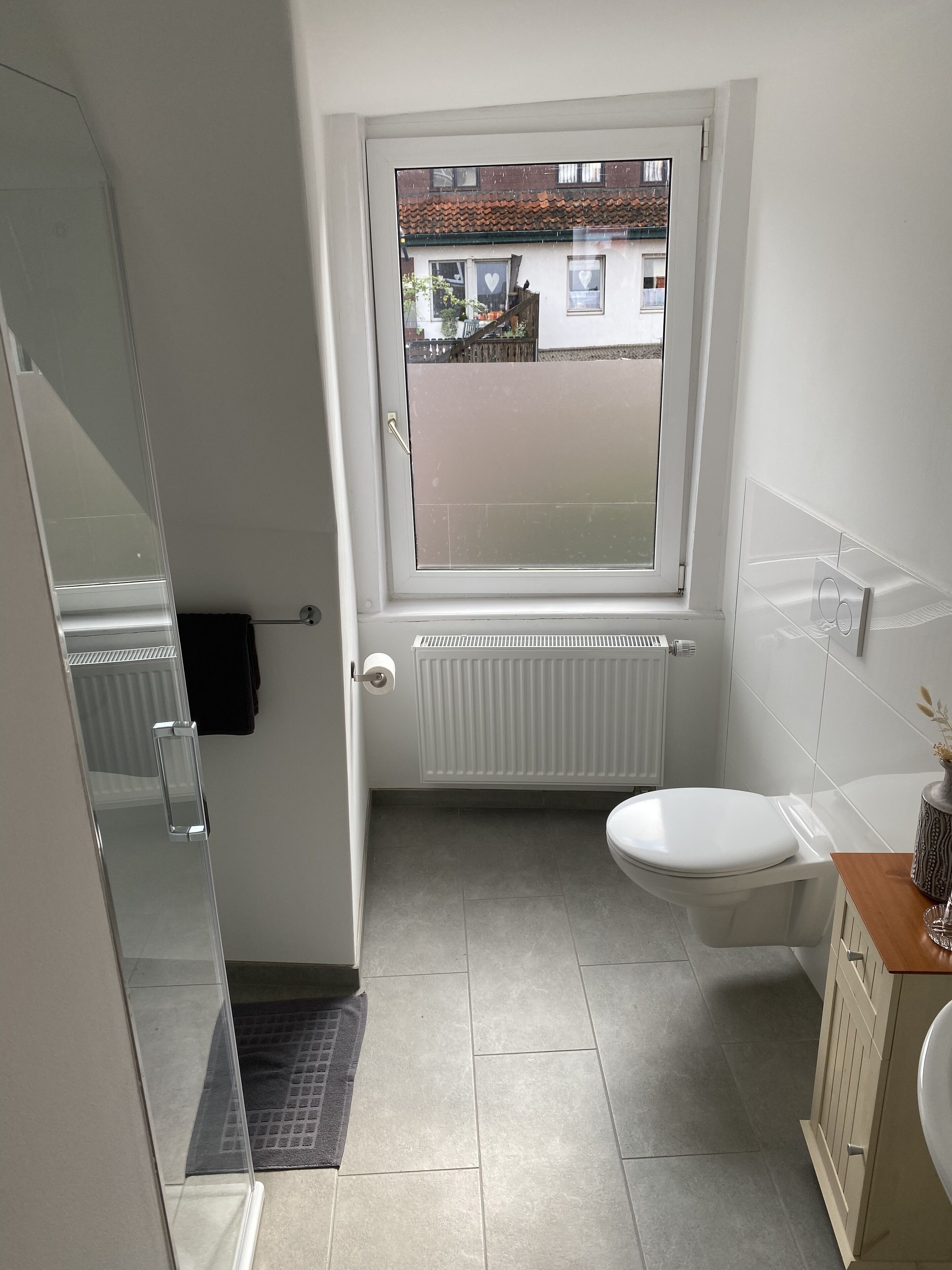 Une petite salle de bain moderne, équipée de toilettes, d’une douche et d’une fenêtre.