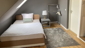 Une chambre à coucher avec un lit, une table de chevet, une lampe et une armoire.