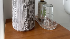 Un vase en céramique grise, orné d’un motif texturé, contenant des fleurs séchées, posé sur un plateau en bois.