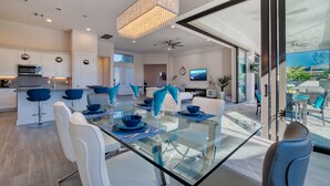 Une cuisine moderne avec des meubles blancs, une table à manger en verre et des chaises bleues.