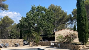 Une piscine dotée d’une terrasse en bois, de murs en pierre et d’un espace salon extérieur.