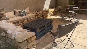 Un espace extérieur aménagé avec un patio, un canapé, une table basse et un fauteuil.
