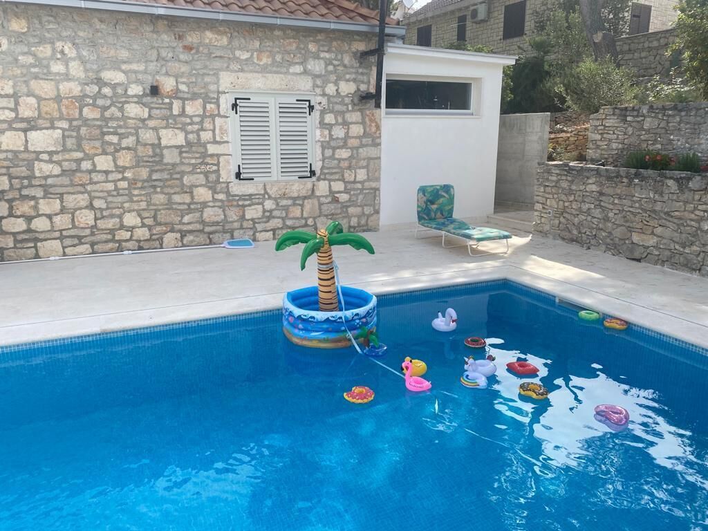 A swimming pool with inflatable toys and a palm tree float.