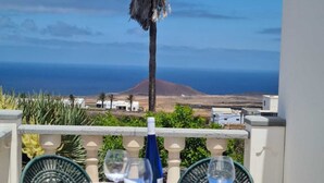 A table set for dining with a view of the ocean and a mountain in the background. - Modern Studio in Rural Tinajo with Patio, BBQ & Coastal Views – Perfect Getaway! (La Costa)
