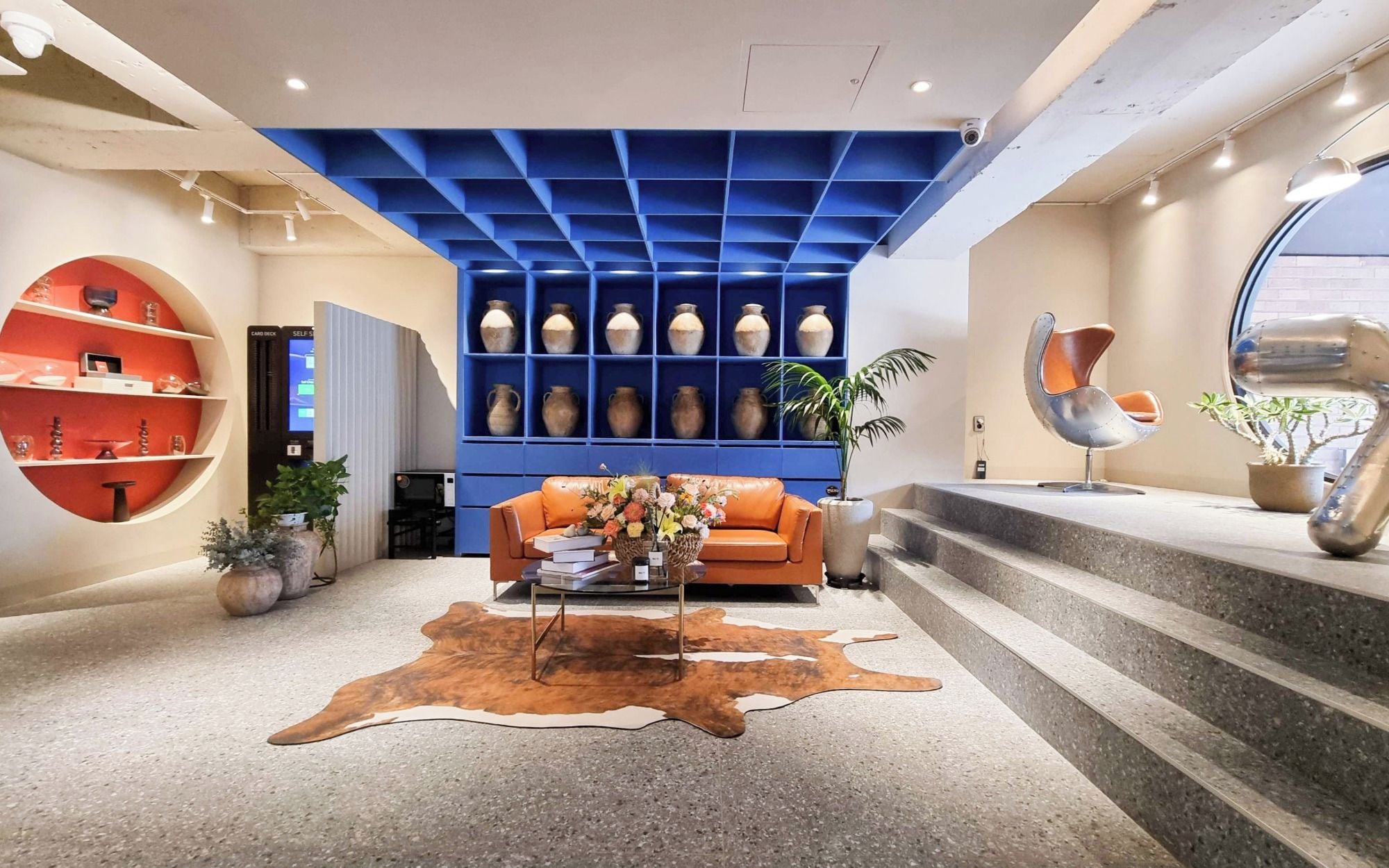 Un interior moderno con techo azul, sofá de cuero, una mesa de centro y alfombra de piel de vaca.