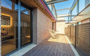 Un patio moderno al aire libre con terraza de madera, puertas de cristal y valla de metal.