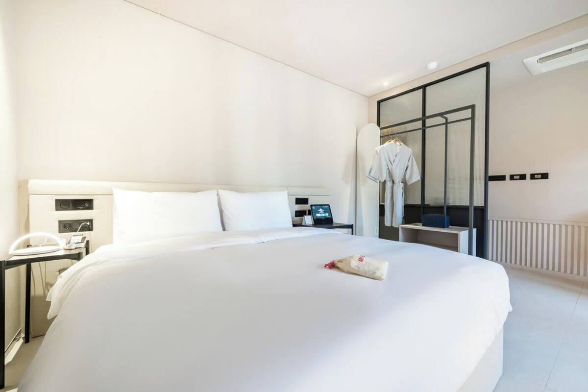 Una habitación de hotel con una cama grande, mesitas de noche, un escritorio y un armario.