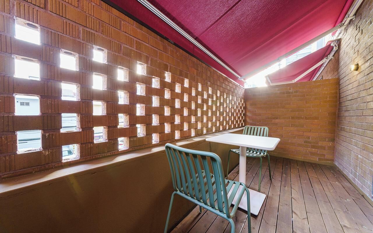 Une pièce avec un mur en briques, un dais rouge et une fenêtre dotée de plusieurs petites ouvertures.