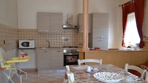Una cocina equipada con microondas, estufa, horno y una mesa de comedor con sillas.