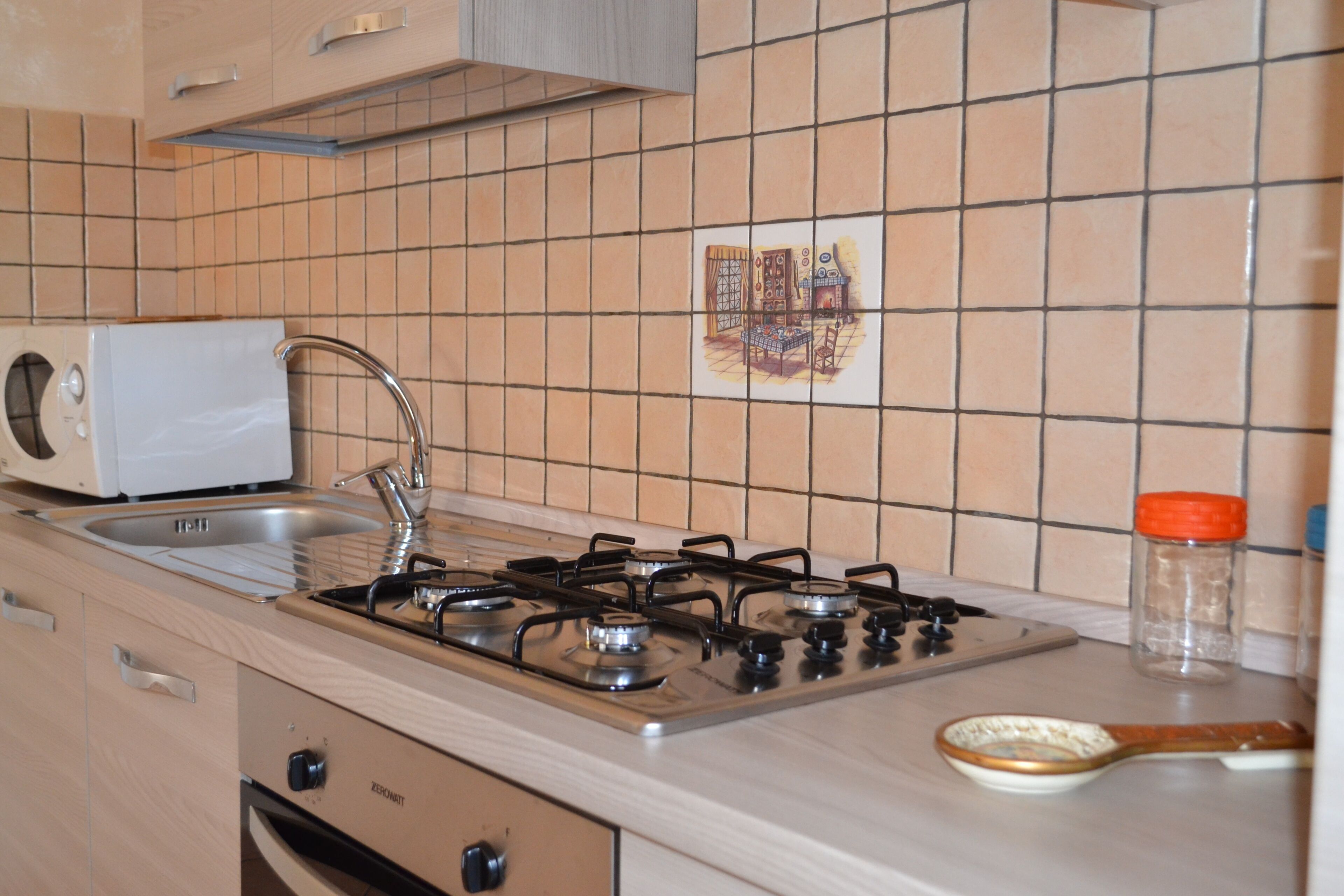 Een keuken met een gasfornuis, een spoelbak en een magnetron.