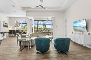 A modern living room with a sectional sofa, two armchairs, a coffee table, and a television. - Intervillas Florida - Villa Leonardo (Cape Coral)