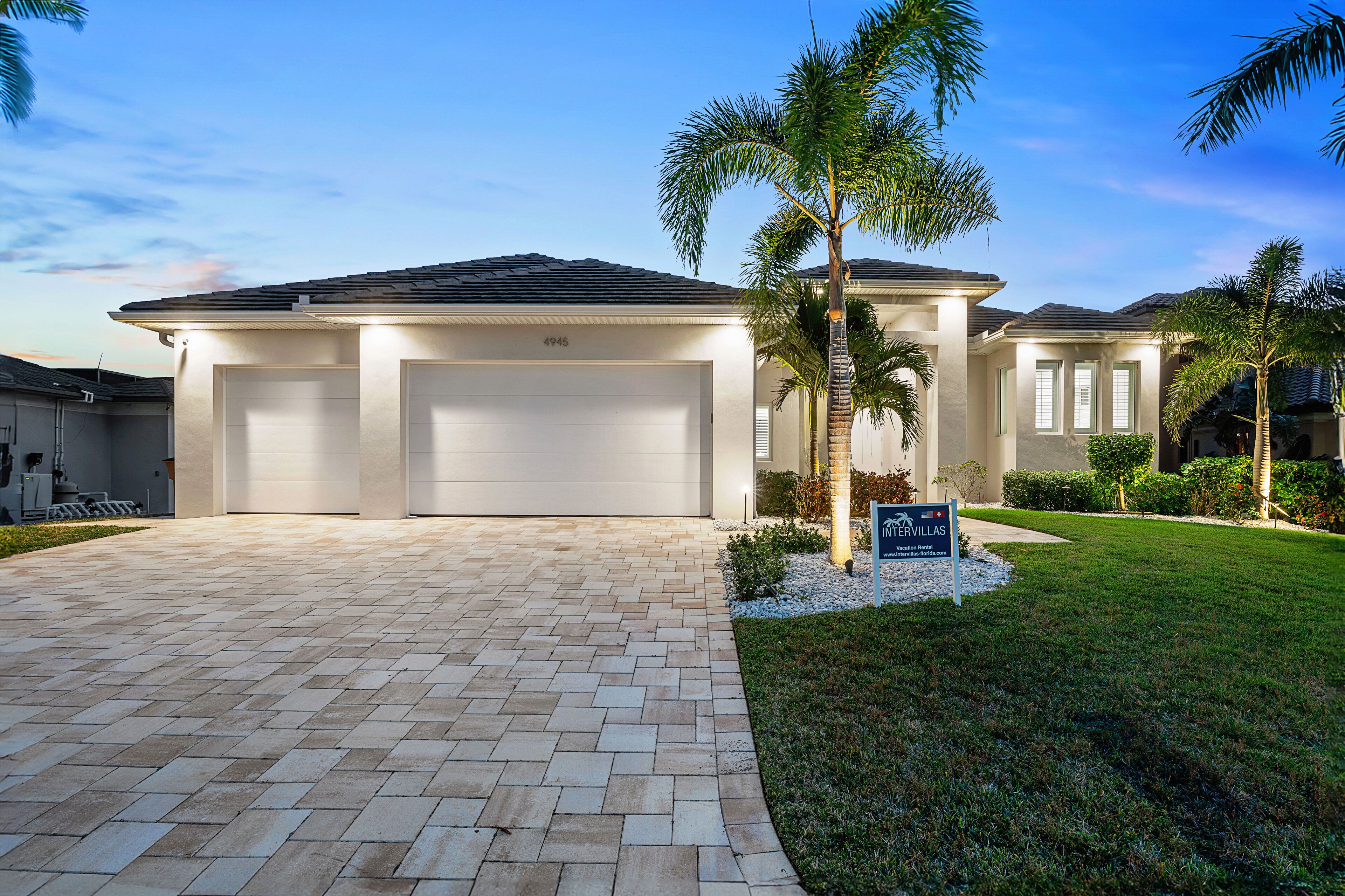 A modern two-story house with a paved driveway and a well-maintained lawn.