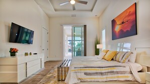 A modern bedroom with a bed, a TV, and a painting of an airplane. - Intervillas Florida - Villa Leonardo (Cape Coral)