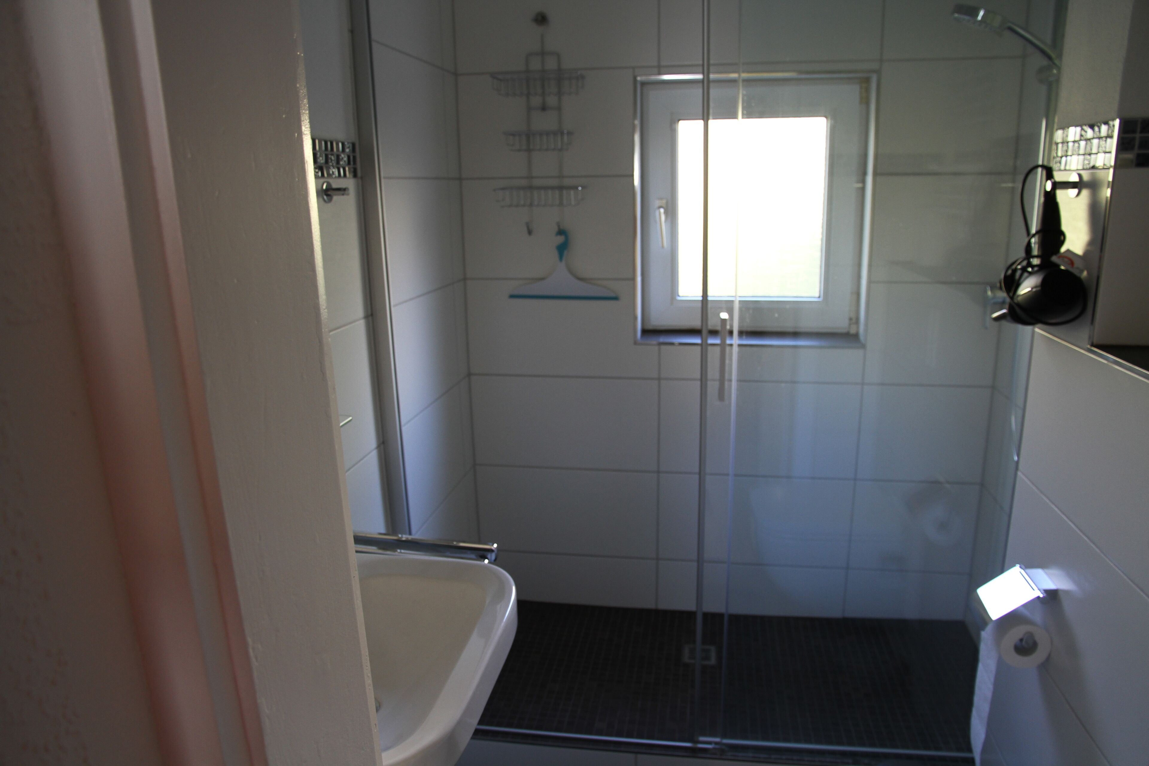 Un petit espace douche fermé, doté d’une porte en verre, d’une fenêtre et de toilettes.