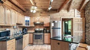 Cucina in legno con isola centrale, elettrodomestici in acciaio inossidabile e parete in pietra.