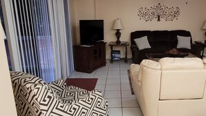 A living room with a beige sofa, a patterned sofa, a TV on a stand, a coffee table, and a decorative wall piece. - Ready to Enjoy BILOXI!! (Biloxi)