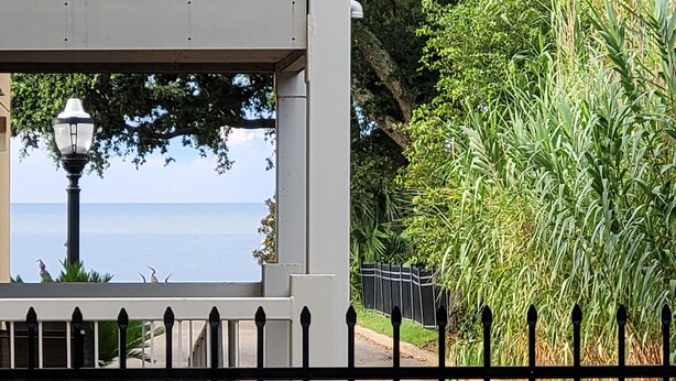 A view from a balcony with a lamp post, a railing, and a body of water in the background. - Ready to Enjoy BILOXI!! (Biloxi)