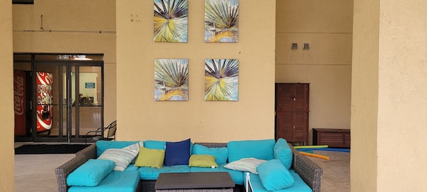 A lounge area with a blue sofa, colorful cushions, and four wall-mounted artworks.