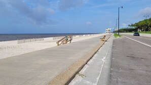 A coastal road with a sidewalk, a wooden fence, and a beach. - Ready to Enjoy BILOXI!! (Biloxi)
