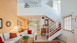 A spacious living area with a white staircase, a sofa set, and a dining table. - Cozy Condo! New low rates for Spring/Summer 2026! Pet Friendly! (Tucson)