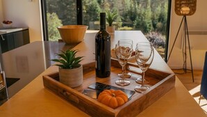 A dining table with a wooden tray, a bottle, and wine glasses.