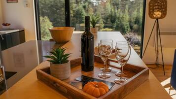 Una mesa de comedor con una bandeja de madera, una botella y copas de vino.