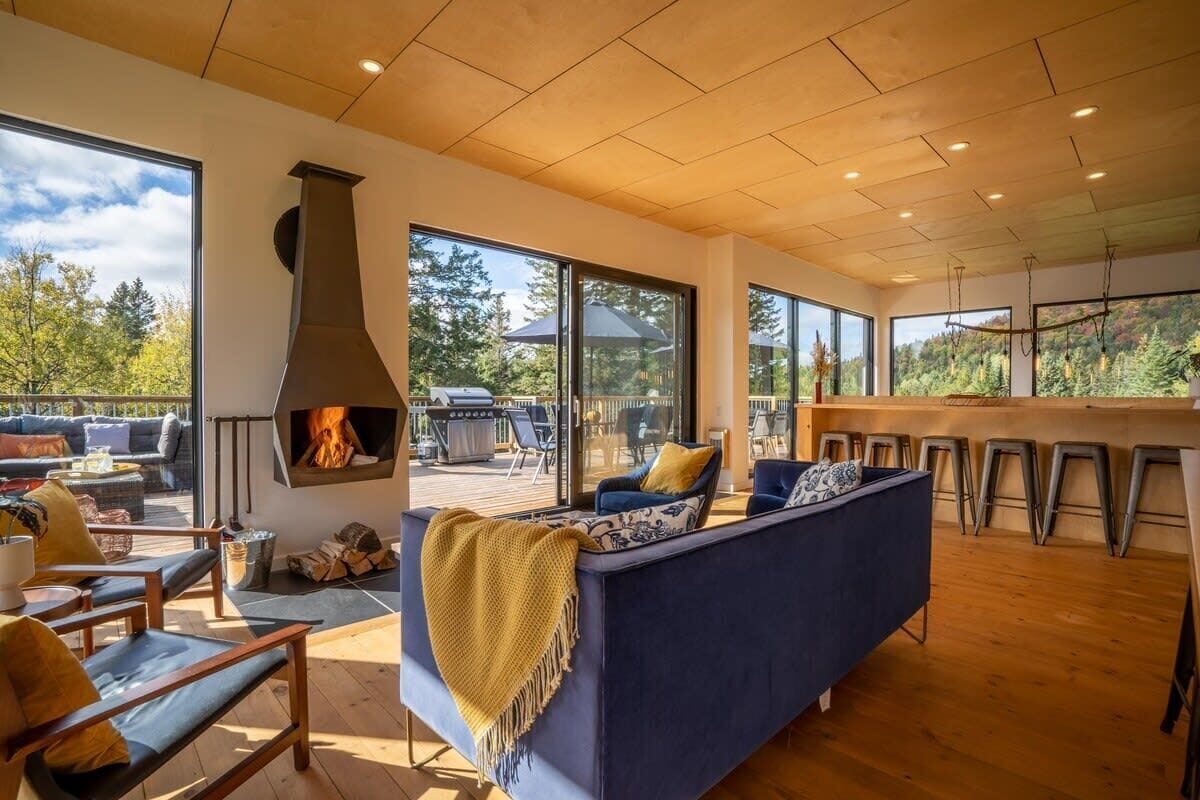 Una sala de estar moderna con chimenea, ventanas amplias y vistas al exterior.