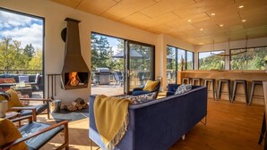 A modern living room with a fireplace, large windows, and a view of the outdoors.