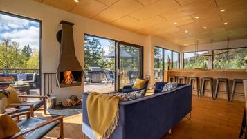 Una sala de estar moderna con chimenea, ventanas amplias y vistas al exterior.