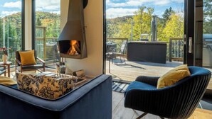 A modern living room with a fireplace, comfortable seating, and a deck with a scenic view.