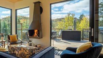 A modern living room with a fireplace, comfortable seating, and a deck with a scenic view.