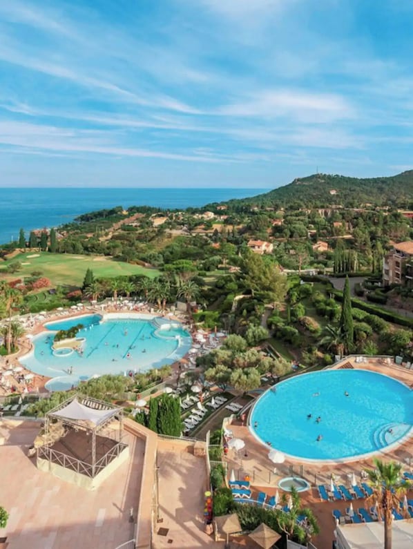 A resort with a large central pool, a smaller pool, and a tennis court.