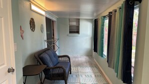 A hallway with a wicker chair, a small table, patterned rugs, and a window with curtains. - Newly Remodeled Weeki Wachee River Retreat (Spring Hill)