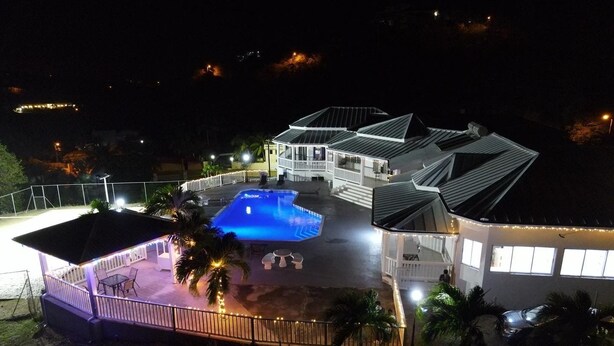 A large, well-lit building with a swimming pool, multiple balconies, and a covered patio area. - Luxury 5BD Villa - Massive Pool & Outdoor Vibe (Gros Islet)