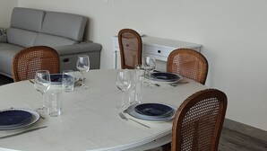 Un coin repas avec une table ronde, six chaises et un miroir au mur.