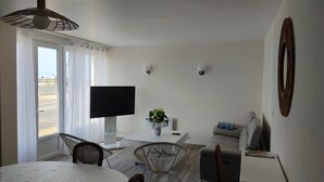 Une chambre d’hôtel moderne dotée d’un grand lit, d’une table à manger avec des chaises, d’un téléviseur et offrant une vue sur l’extérieur.