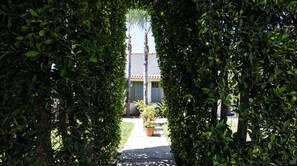 Stroll through lush surroundings to a charming building with a traditional tiled roof and green window frames.