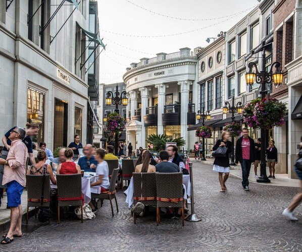 Experience the vibrant atmosphere of this bustling urban street, lined with traditional buildings and outdoor seating areas.
