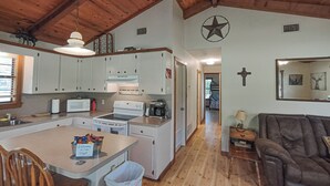 A spacious kitchen with white cabinets, a stove, and a dining area with a table and chairs. - Longhorn Lake House - Arcridgeranchresort.com (Ben Wheeler)