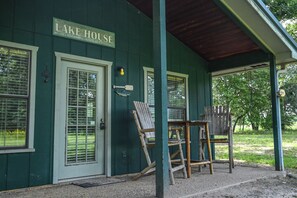 Un bâtiment écologique portant l’inscription « LAKE HOUSE », doté de grandes fenêtres, d’un porche couvert et d’un espace salon extérieur.