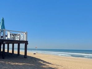 A beach with a wooden deck and a flag. - Superbly Modern and Airy Two Bedroom Seaside Apartment with Balcony (Bijilo)